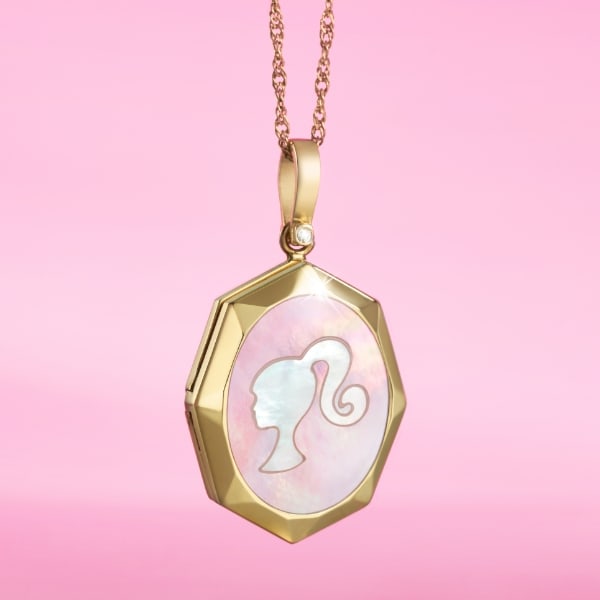A pink background with our limited-edition Barbie™ x Fossil gold-tone locket featuring mother-of-pearl embellishments, a gold-tone stainless steel chain with a lobster clasp and finished with a stylish Barbie silhouette.